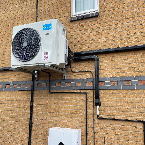 Outdoor unit with neat trunking Outdoor air conditioning condenser with neat black pipe trunking on a brick wall